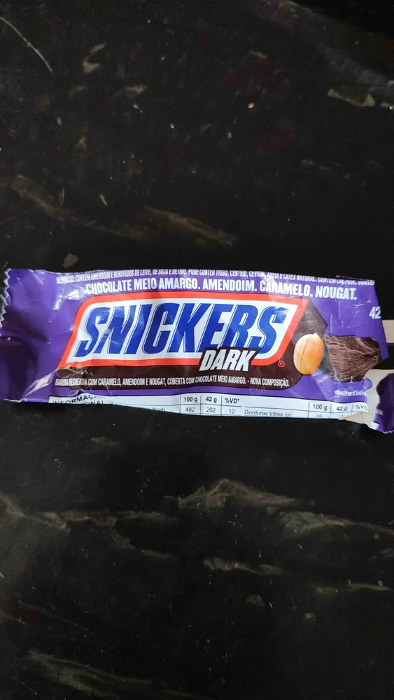 Barra recheada com caramelo, amendoim e nougat, coberta com chocolate meio amargo