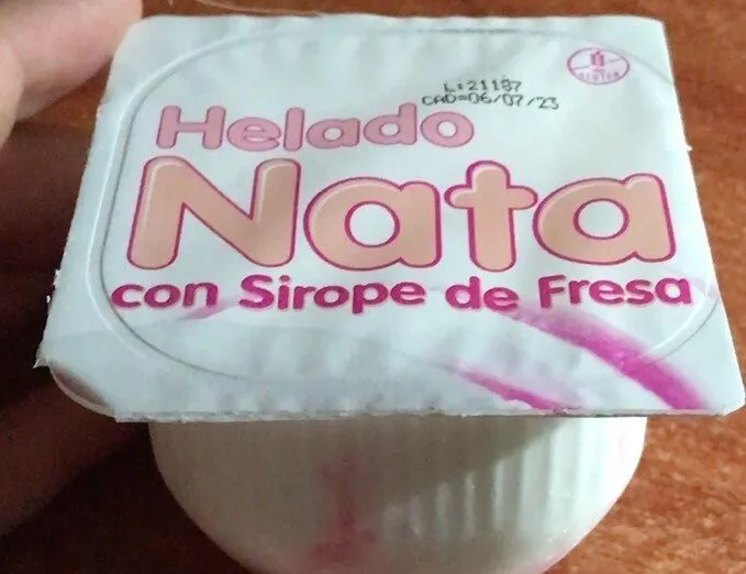 Tarrina de helado de nata con sirope de fresa